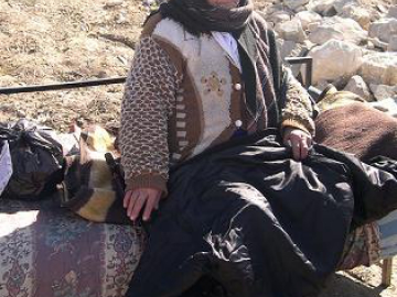 امرأة عجوز تجلس على صوفا في المكان المحدد حيث كان منزلها قبل الهدم.